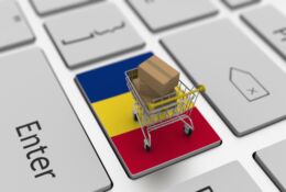 pulpit laptopa z rumunska flaga i koszykiem z zakupami