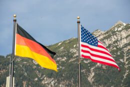 Wawing American and German flags against mountains of rocks and blue sky