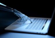 yborg hand pressing a keyboard on a laptop in dark blue background