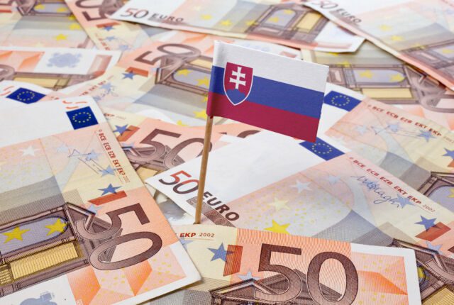 Flaga Słowacji wbita pomiędzy leżące banknoty euro