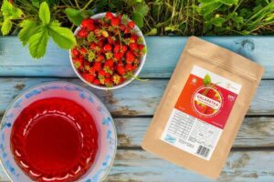 The photo features a sugar-free wild strawberry-flavored jelly in eco-friendly paper packaging and prepared in a garden