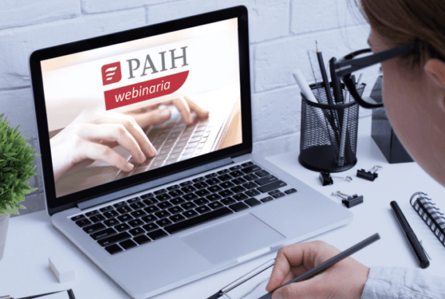 osoba siedzaca przy laptopie i napis PAIH webinaria